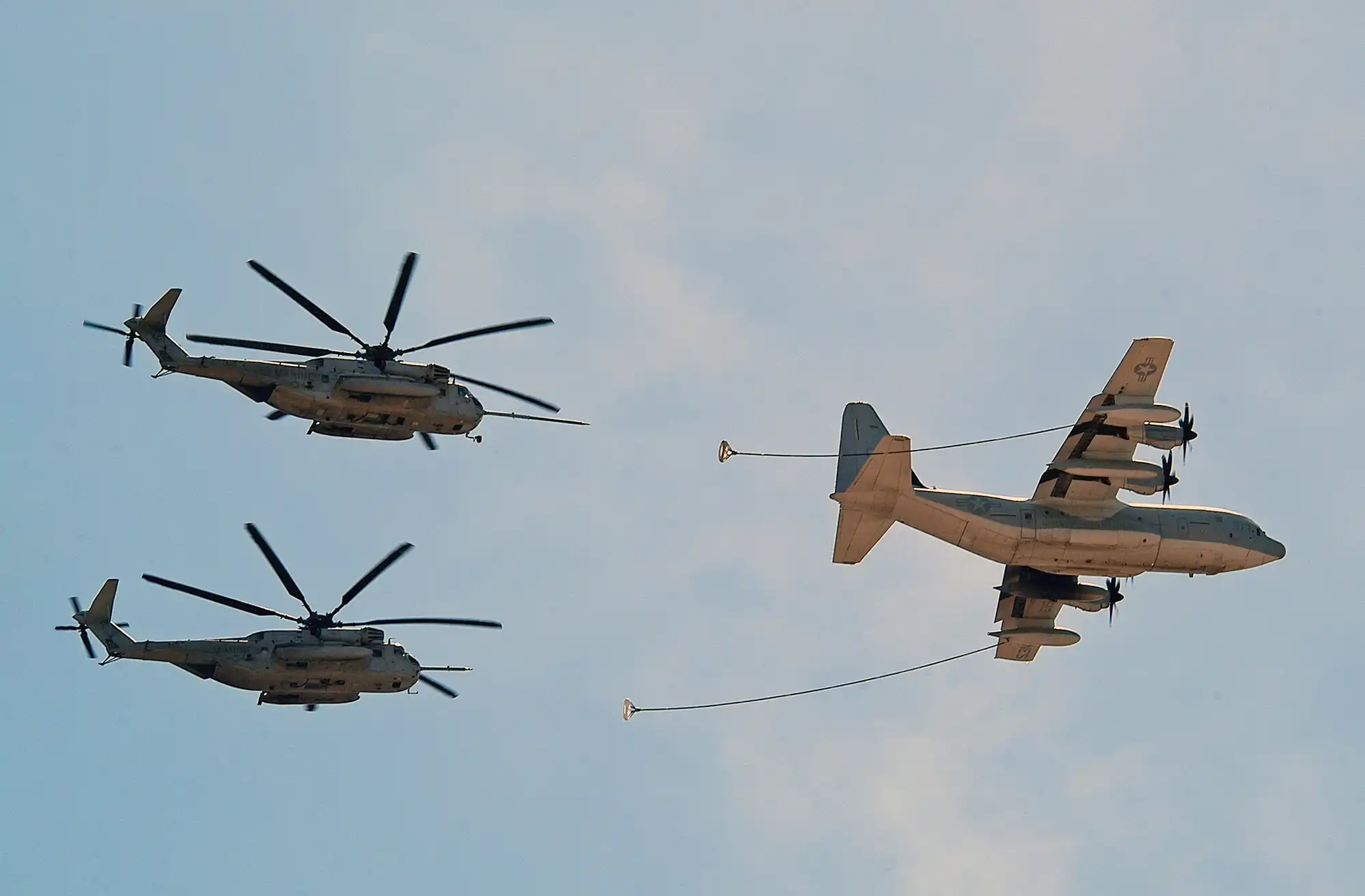 C-130 tanker refueling two heavy-lift helicopters
